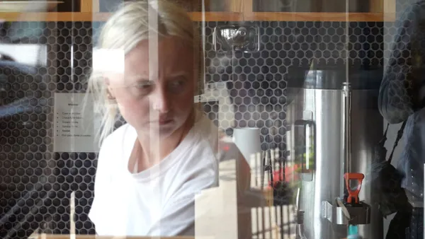 A cafe employee works behind a window.