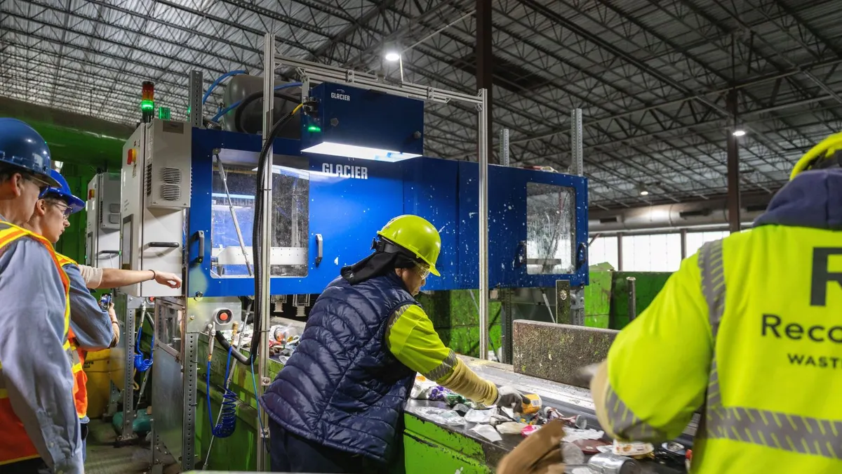 workers pull material off a conveyor at a recycling facility