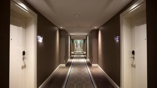 A man walks down a hotel corridor.