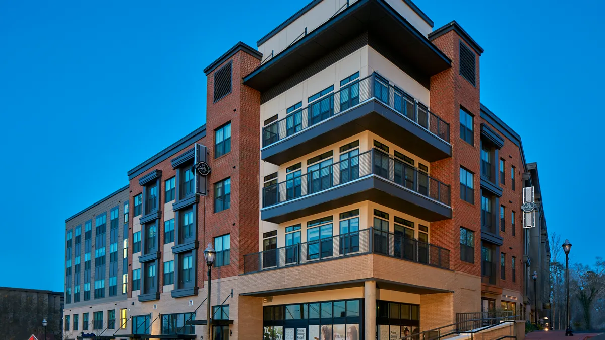 Five-story brown and brick apartment building.