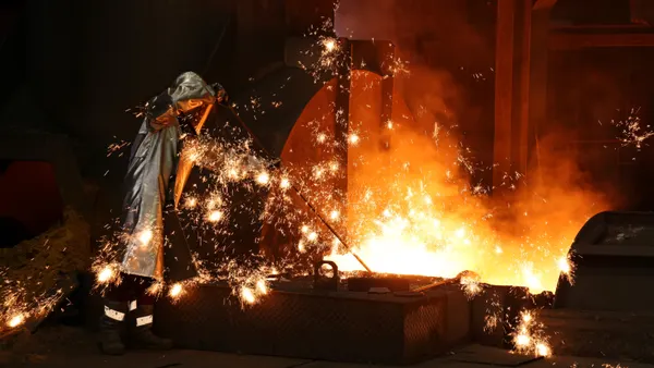 Sparks fly as a worker takes a sample of molten iron.