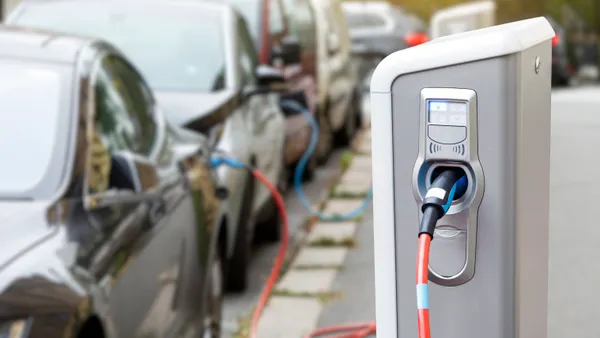 Close up of EV charger with cars parked in background