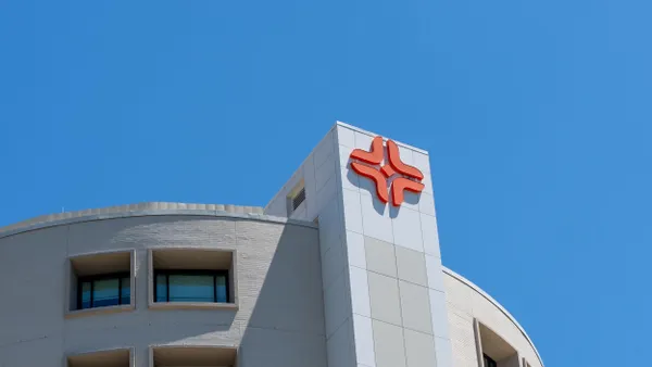 Logo of HCA Houston Healthcare on the top of a modern hospital building under a clear blue sky.