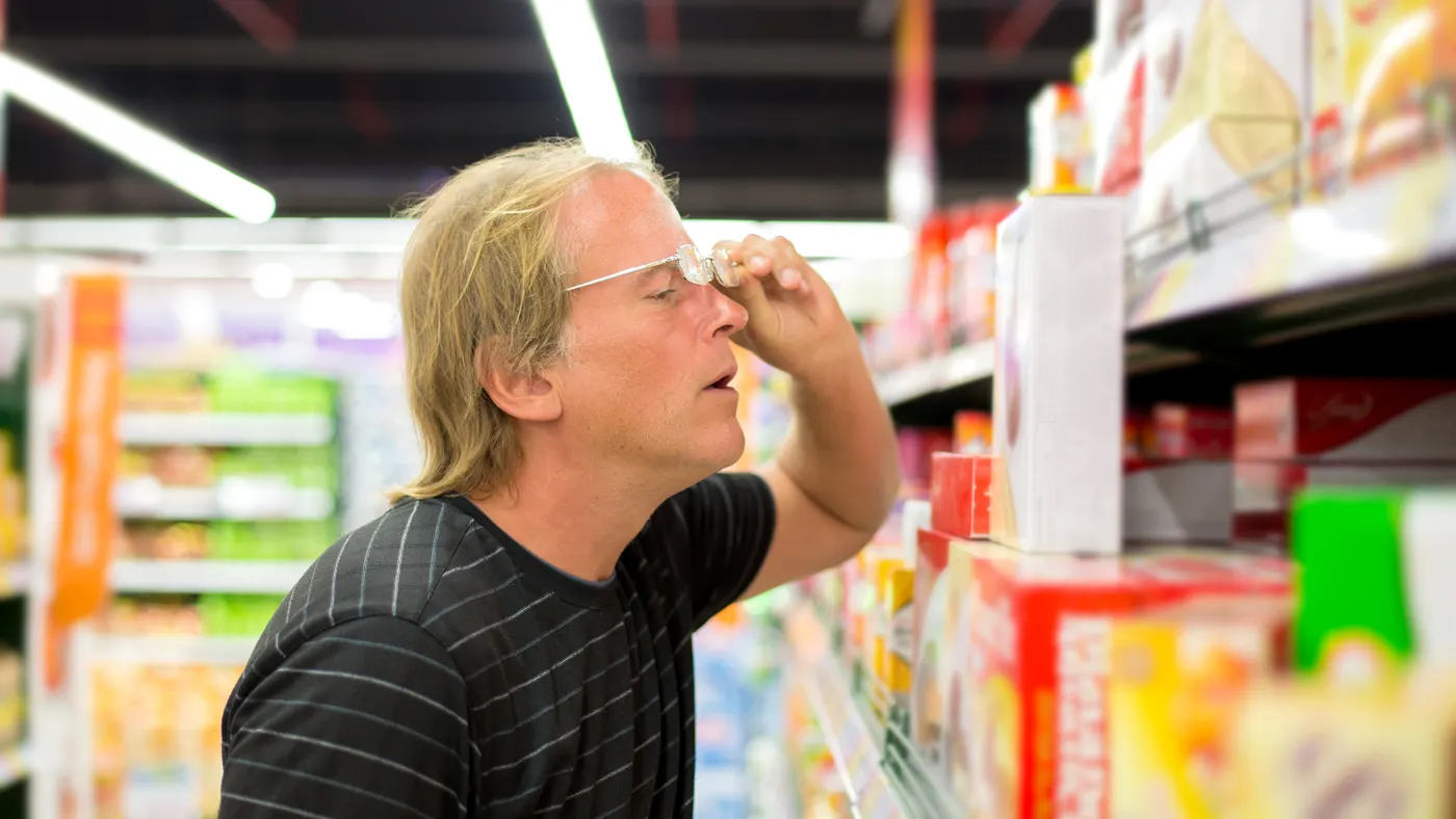 A person looks very closely at a items on a shelf.