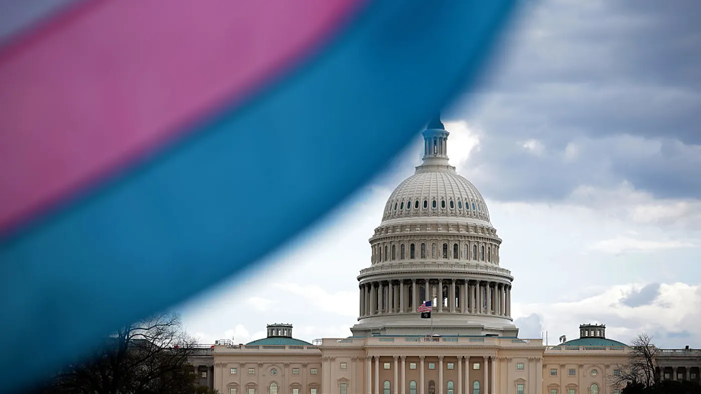 The White House is pictured behind a waving transgender pride flag.