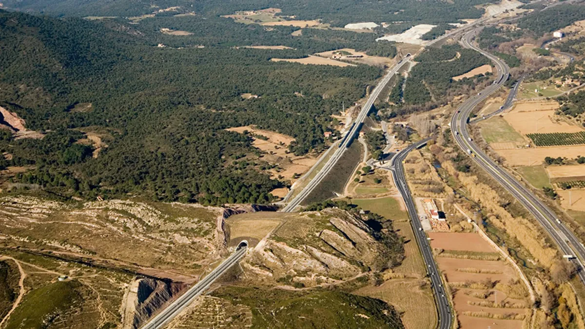 Aerial view of a rail line cutting through forest and farmland.