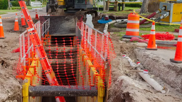 A trench surrounded by construction safety protections.