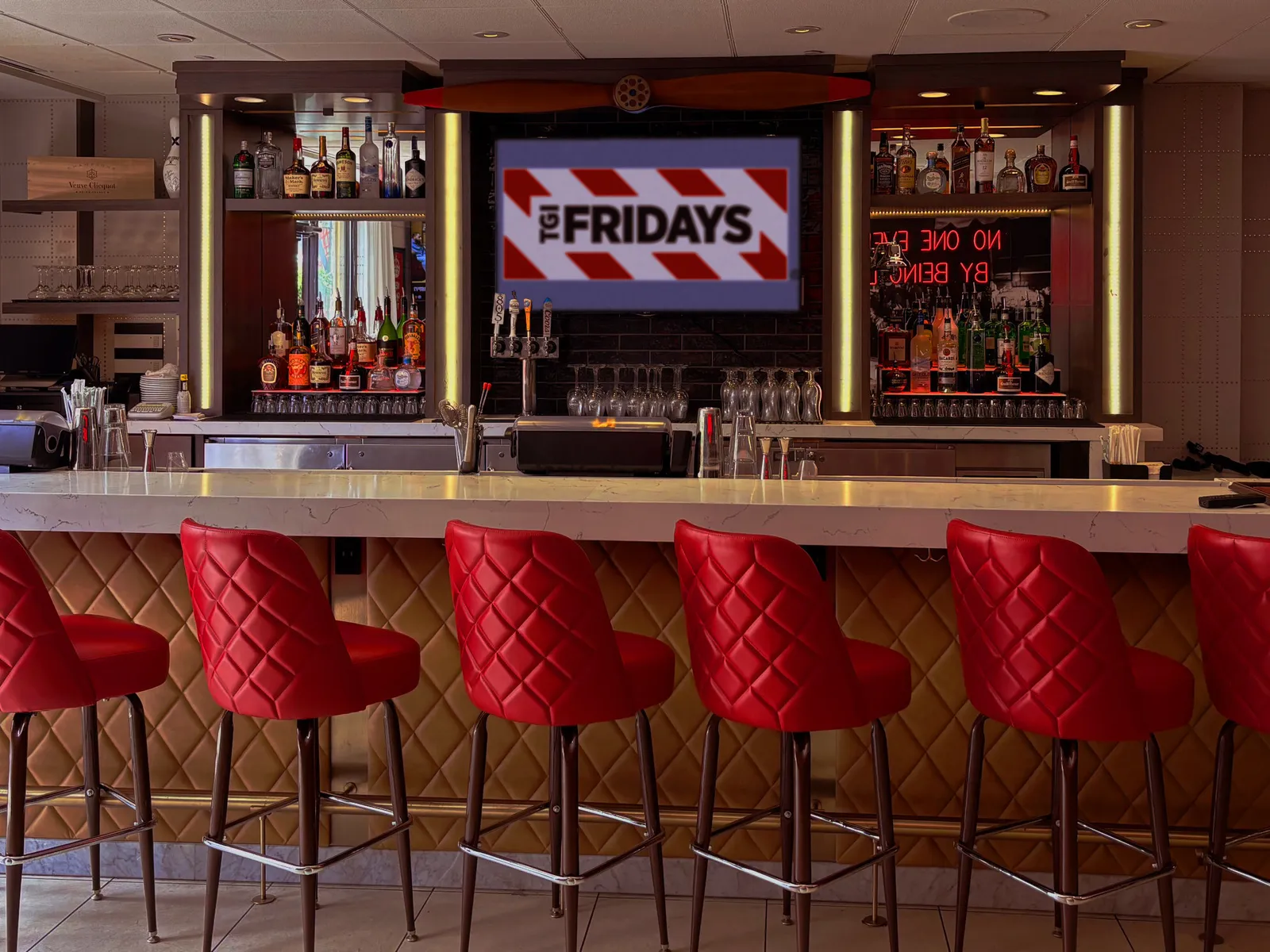 An image of a bar with red chairs and TGI Fridays signage in the background