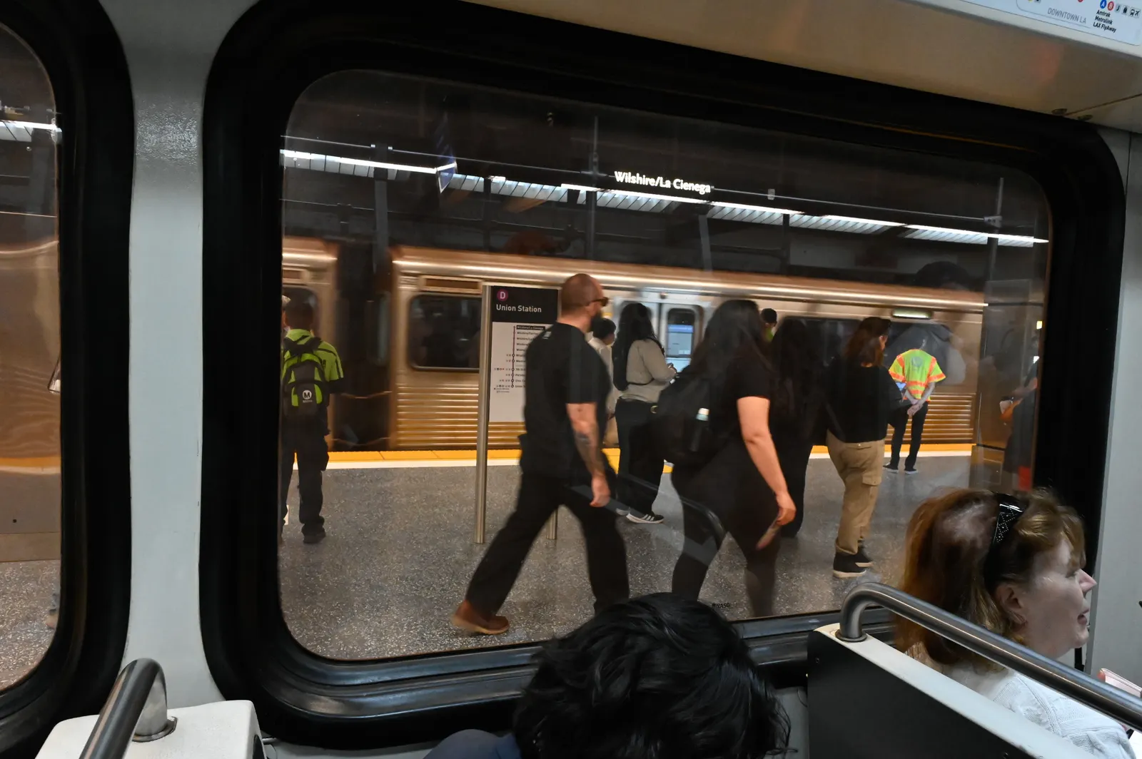 People walking on a train station platform seen from inside a subway train.