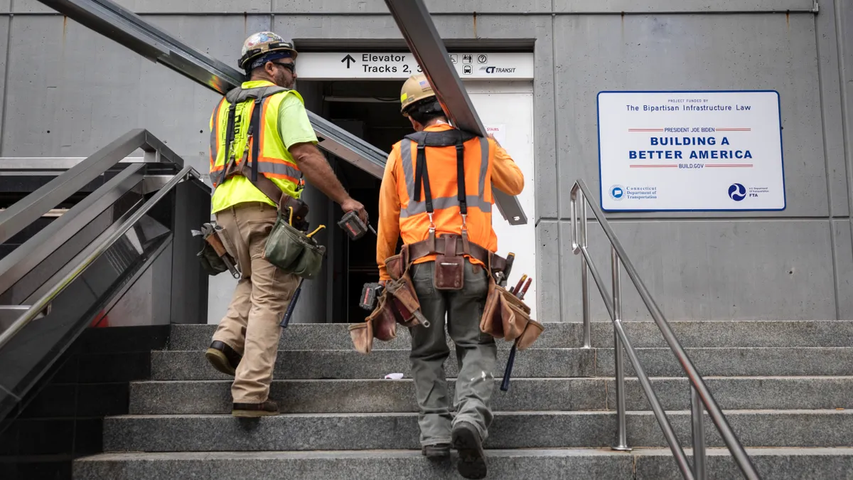 Construction workers carry building materials through the Stamford Transportation Center