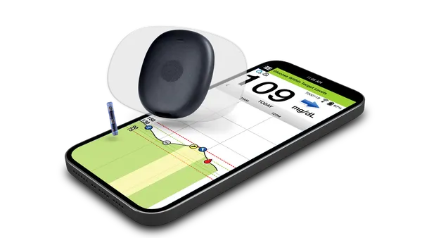 A black reader is shown on top of a phone with a blood glucose reading.