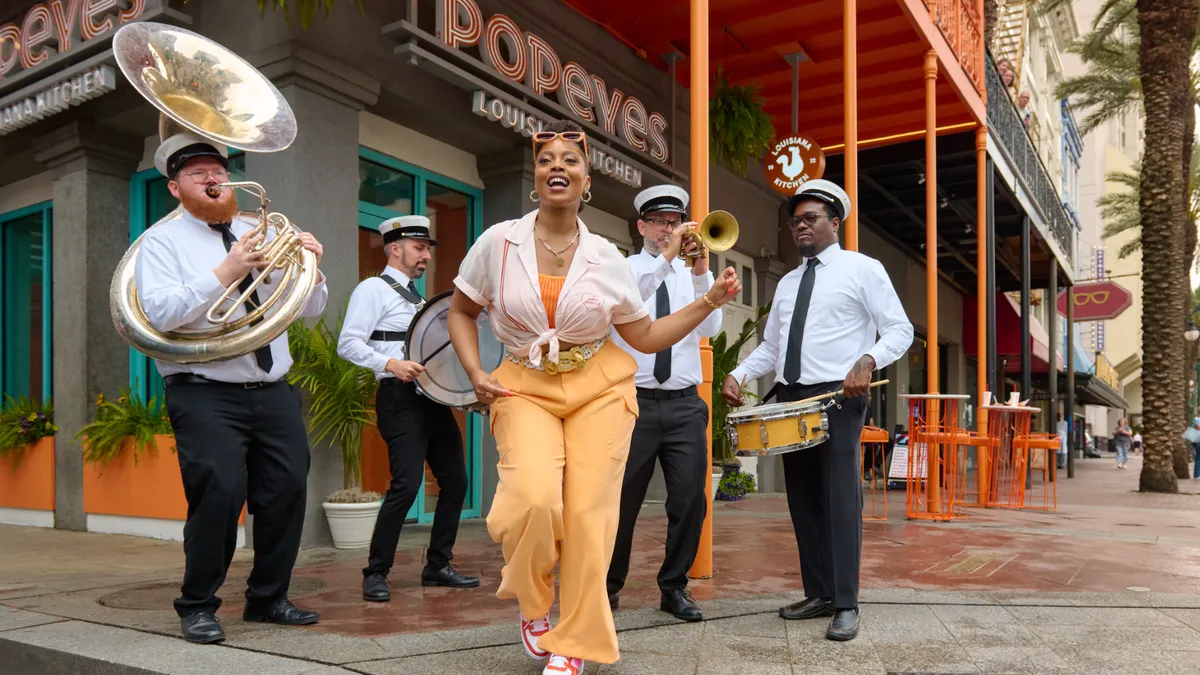 A women dances in front of a jazz band in the street.