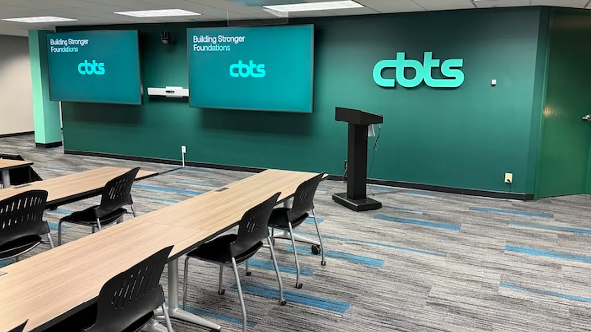 The interior of an office with filled with tables and digital screens bearing the CBTS corporate logo.