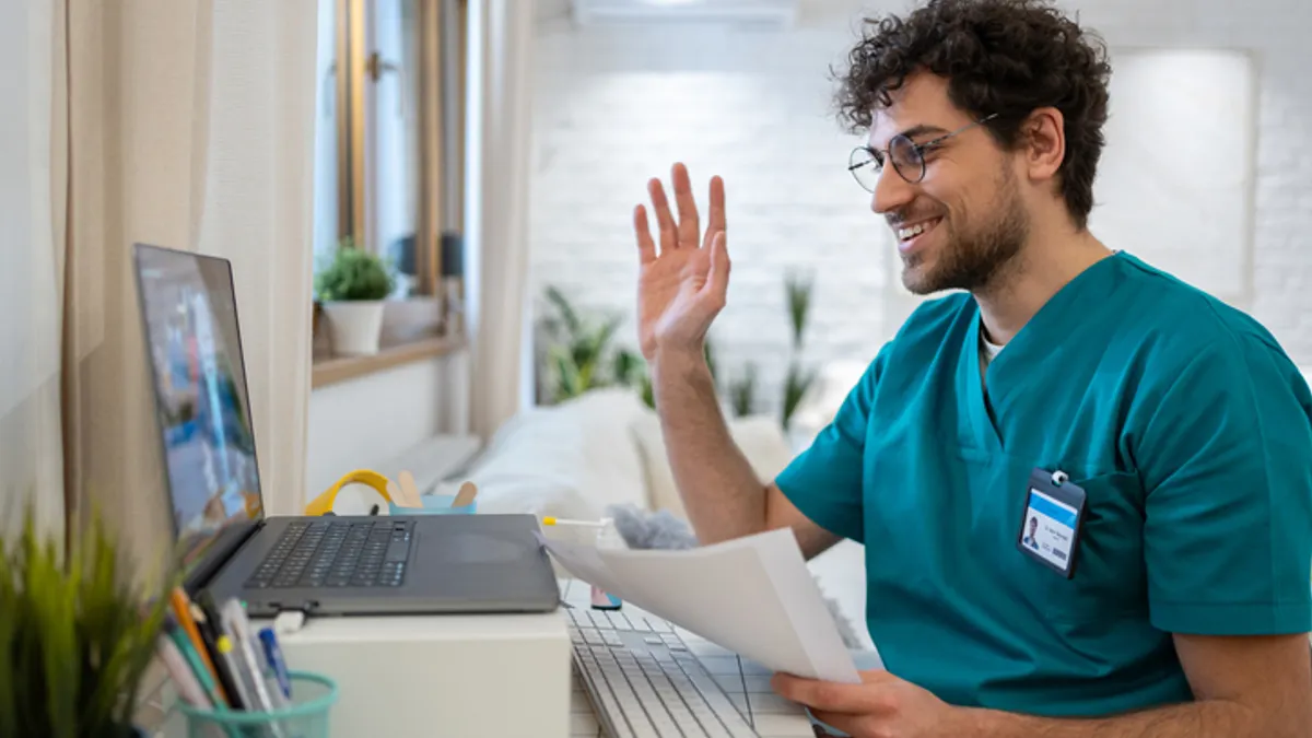 Nurse in scrubs, waving back to a patient during an video call