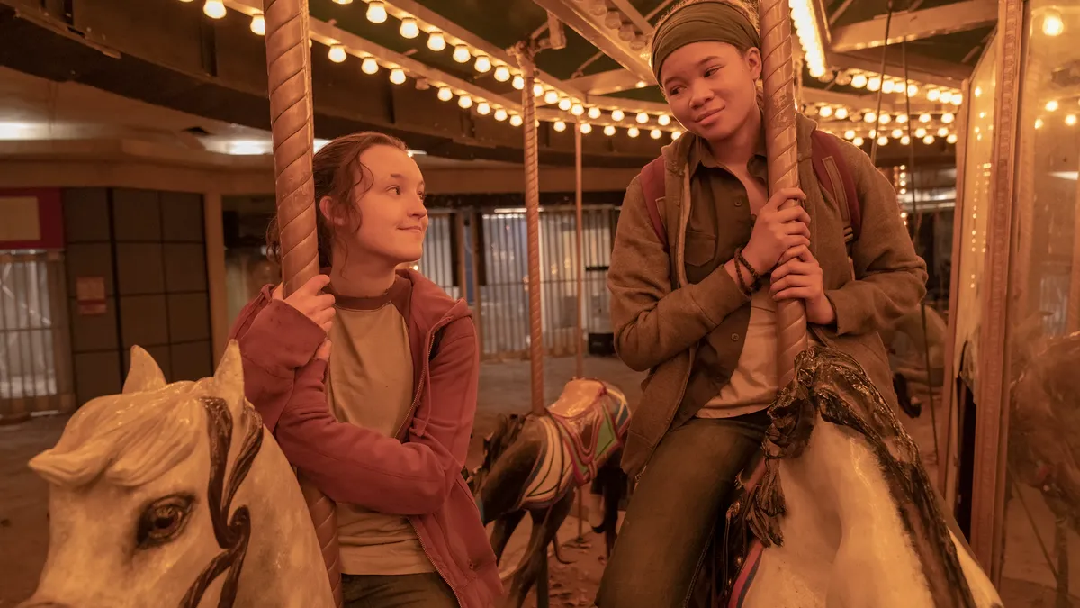 Two people on a carousel, smiling in each others' direction.