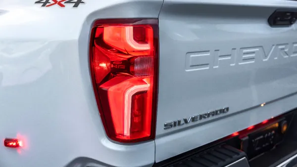 The left rear corner of a white 2024 Chevy Silverado HD 3500 showing the left rear tail lamp and 4x4 label.