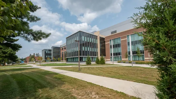 A shot of a building during daylight from an angle, in front of a green lawn.