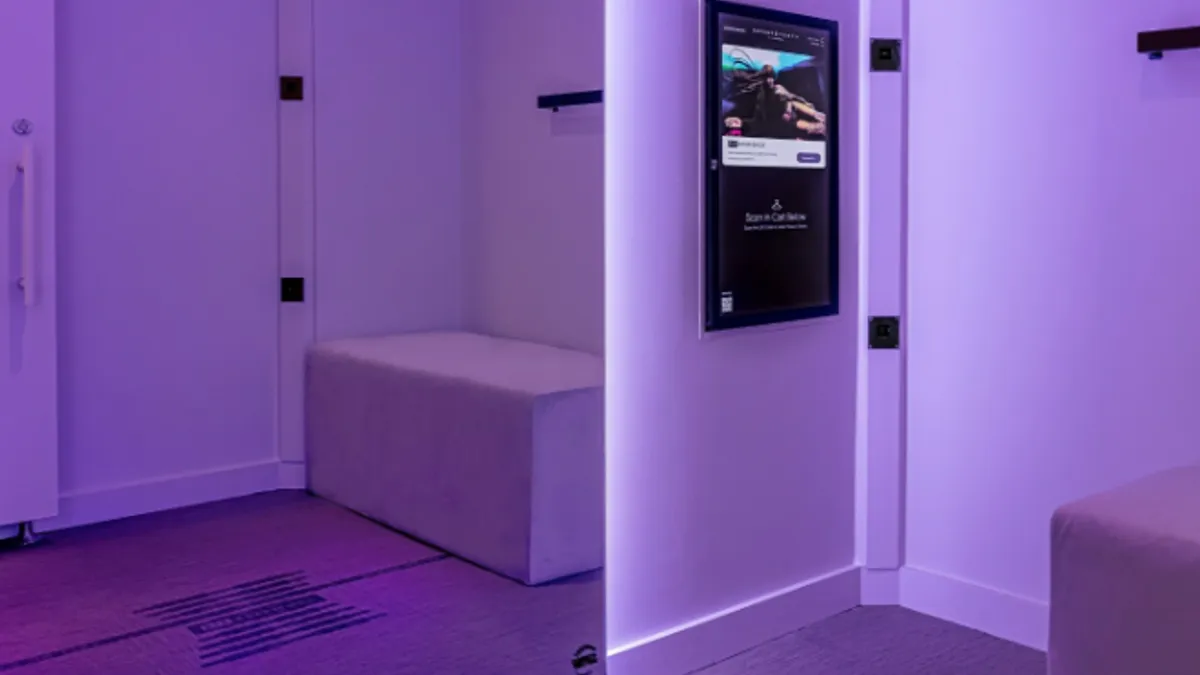 Dressing room in purple light with a large screen in one corner.