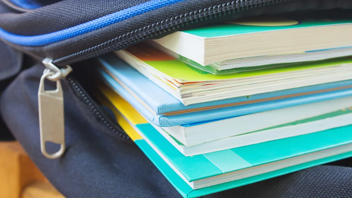 A pile of books sits inside a partially opened blue backpack.