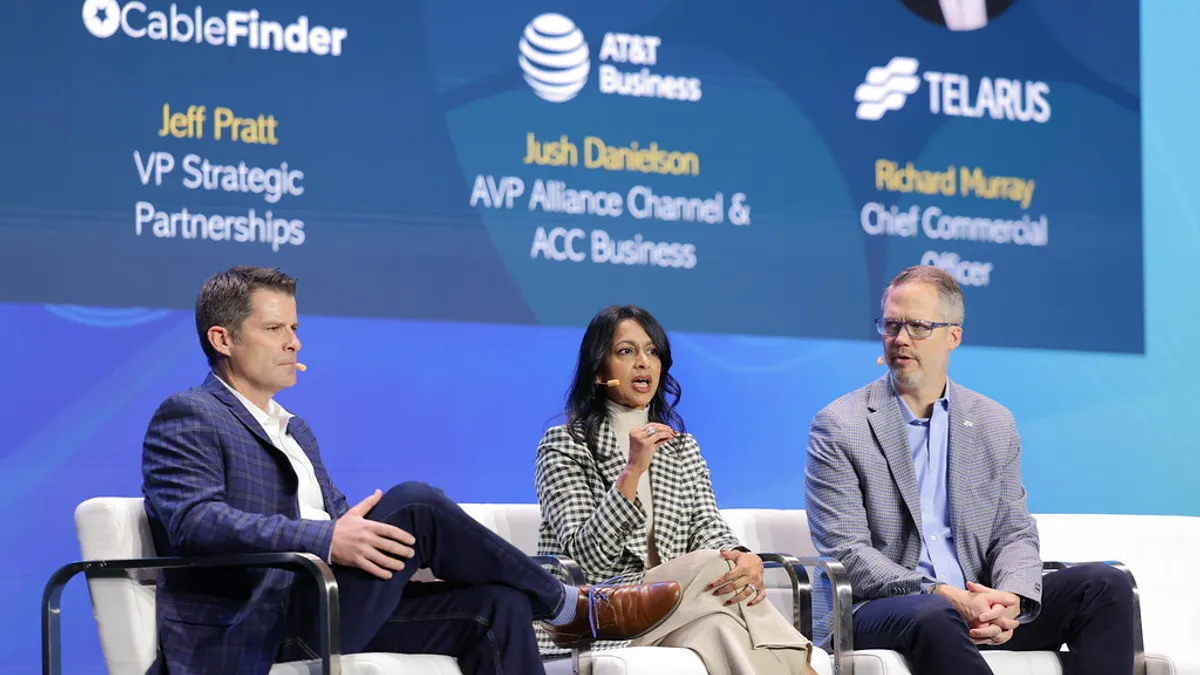 Three people sit on a stage