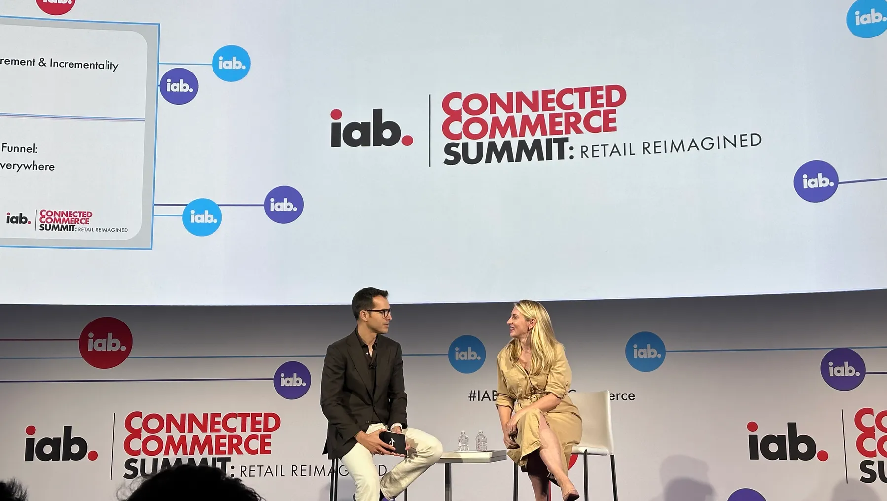 Man and woman sitting next to each other on stage during a panel at IAB's Connected Commerce Summit