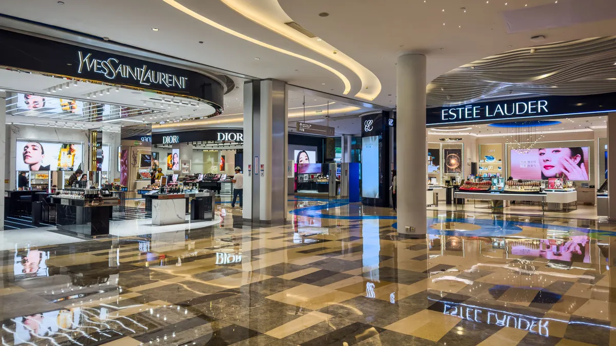 The interior of a well-lit mall shows beauty counters from YSL, Estee Lauder and Dior.