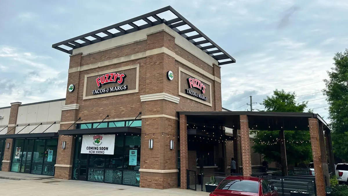 A photograph of a brick building with signage that says "Fuzzy's Tacos and Margs."