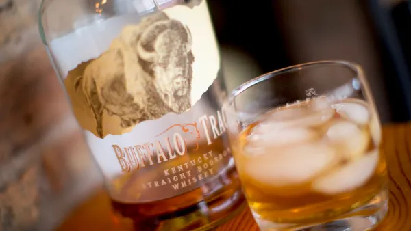 A bottle and glass of Buffalo Trace are sitting next to each other.