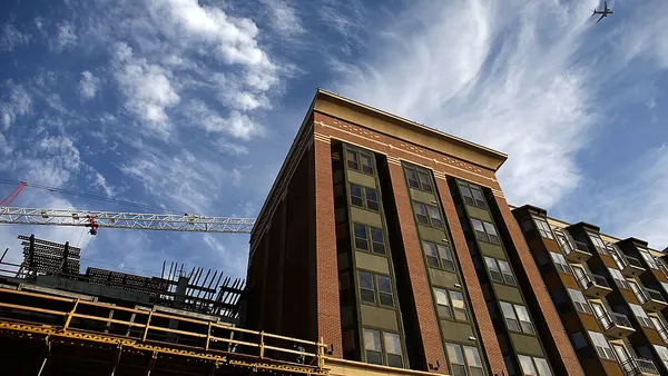 Aerial view of an apartment building under construction with a crane above.
