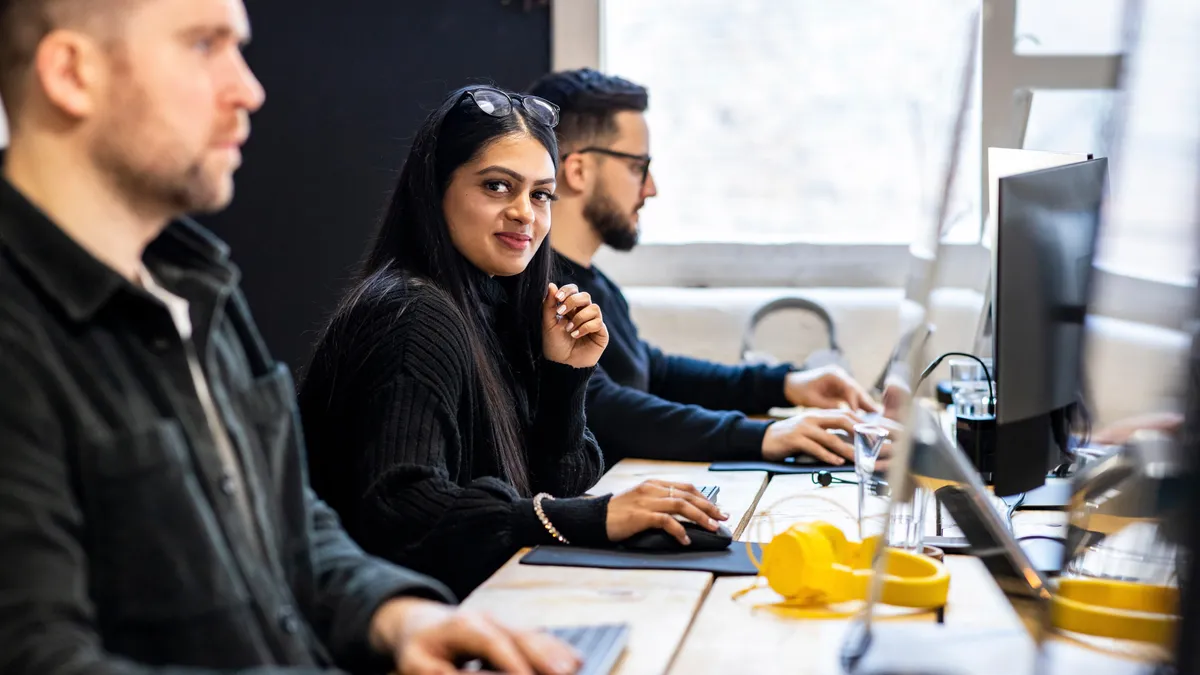 Smiling businesswoman sitting with colleagues at desk