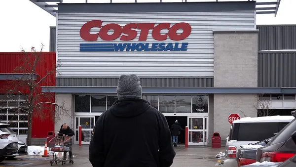 A man stands in front of Costco exterior, in the parking lot