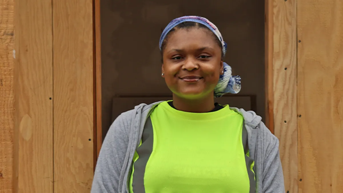 Female in neon green shirt standing infront of wooden room