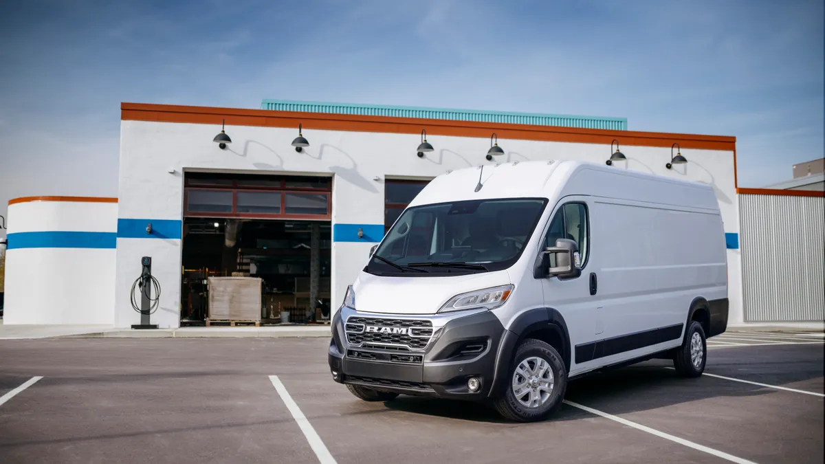 A white Ram ProMaster electric cargo van parked in front of a service facility.