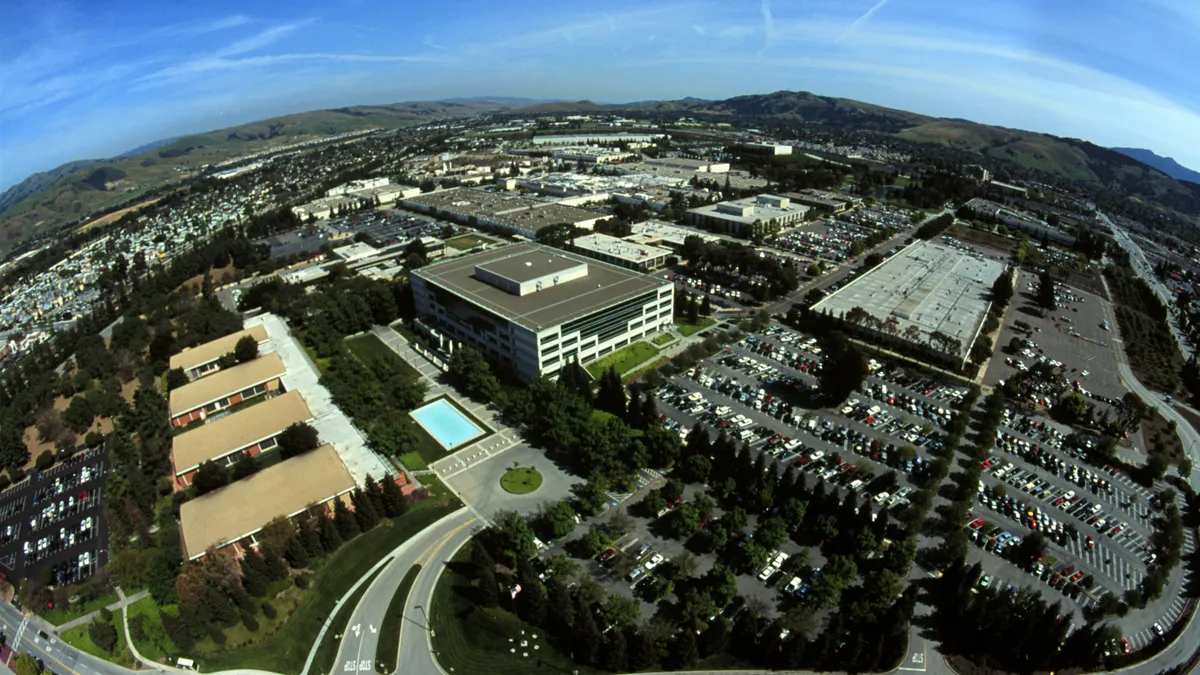 An aerial view of office buildings in San Jose Calif. with green hills and blue sky in the background.