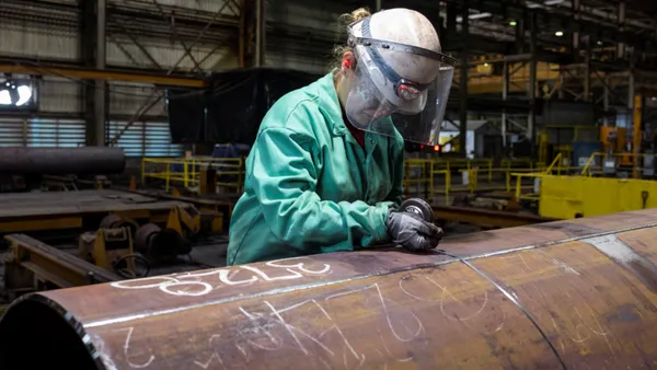 A person wearing personal protective equipment inspecting steel.