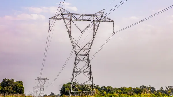 Power line towers crossing a scrubby field.