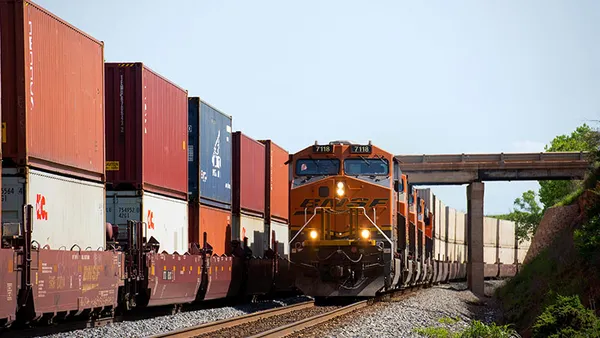 A BNSF locomotive sits by containers in an intermodal facility.