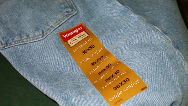 A pair of jeans with their size label are laid out on a blank background.