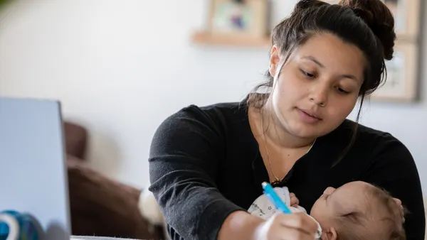 A person writes while holding a baby.