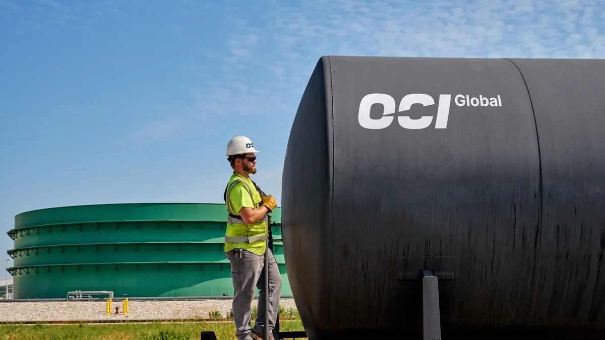 A hard-hat worker stands near OCI Global equipment.