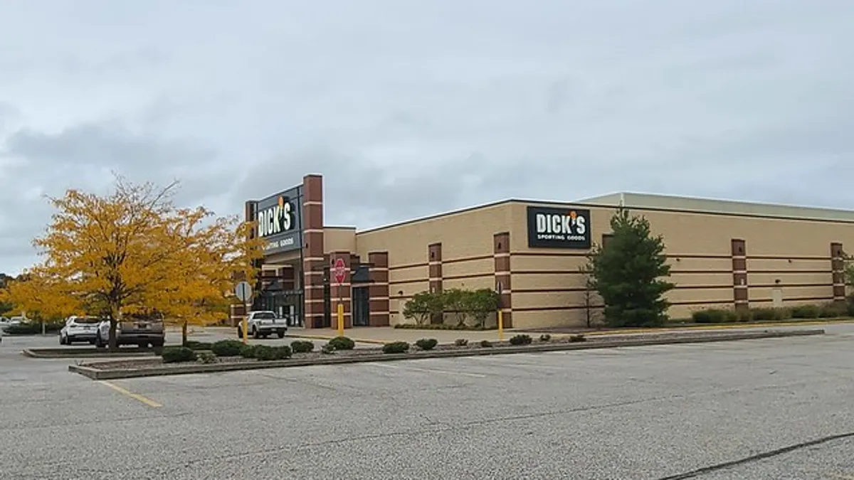 A sporting goods store, with a yellow tree to the left.