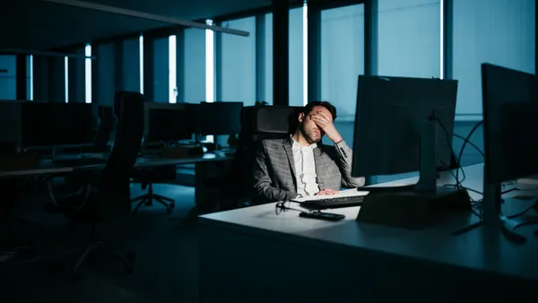 A smartly-dressed businessman is resting in his office in front of his computer.