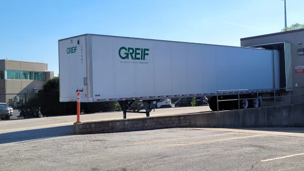 A trailer with the Greif logo on the side is parked at a loading dock.