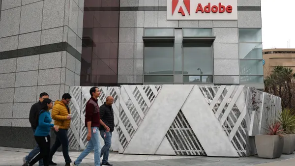 Pedestrians walk by a sign at Adobe headquarters on December 12, 2024 in San Jose, California.
