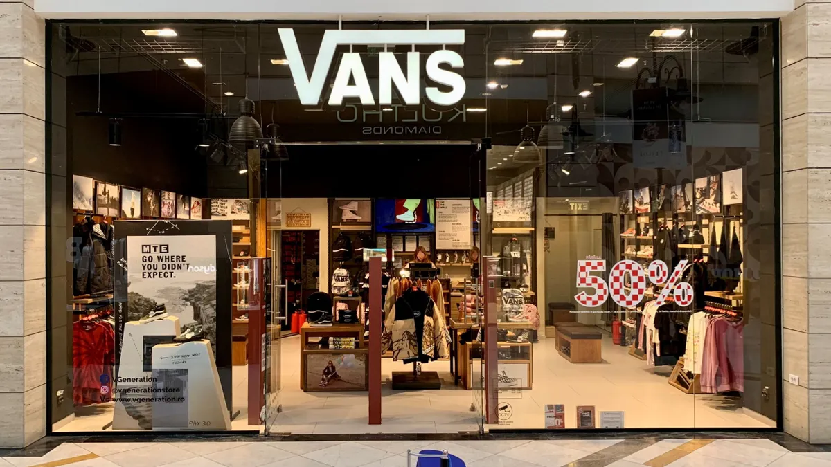 A Vans store is pictured in a mall, with a sign advertising a 50% off sale.