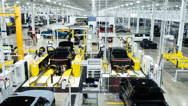 The interior of Rivian's electric vehicle factory in Normal, Illinois, showing R1T pickups on the assembly line.