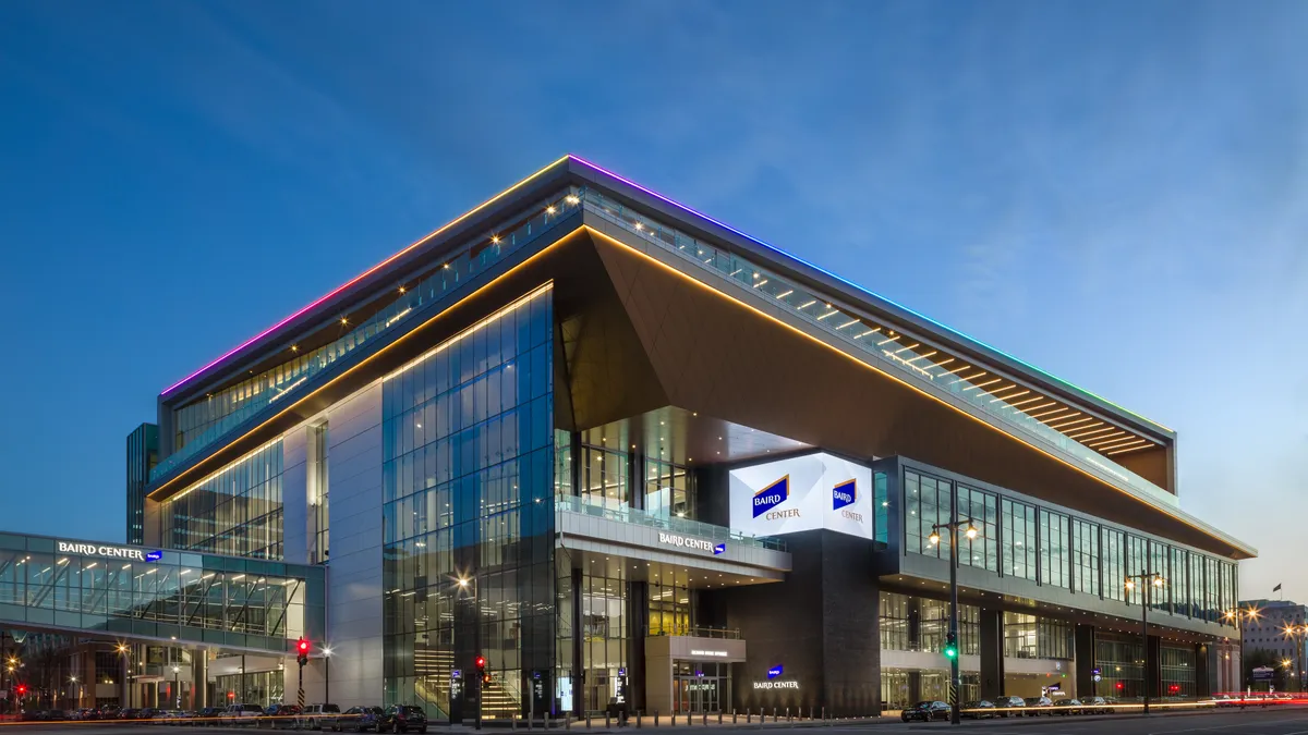 The exterior of a large building at dusk, with large LED screens depicting different people and products