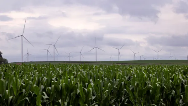 Wind turbines tower over a rural landscape.
