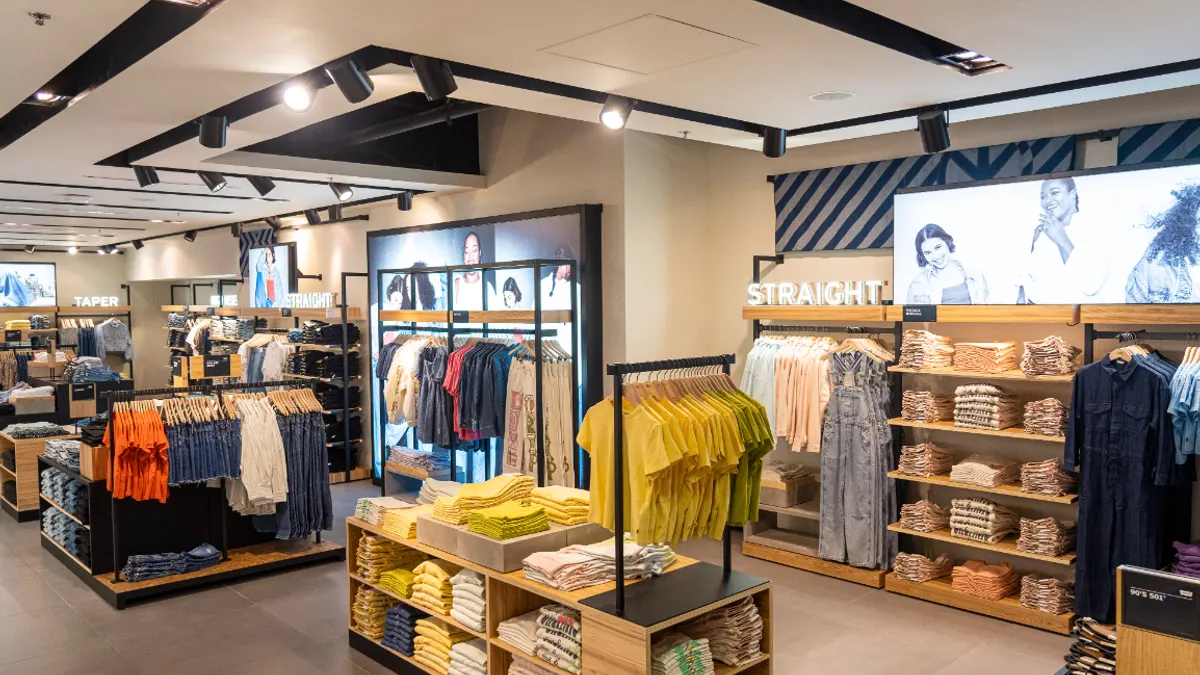 The interior of a Levi's shop-in-shop, with jeans and t-shirts against a wall and a central island with shirts folded and hanging.