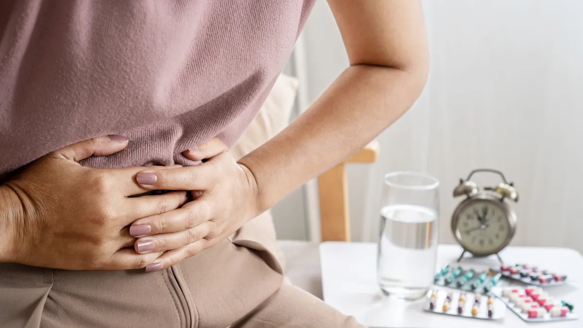 A woman's hands over her abdomen.